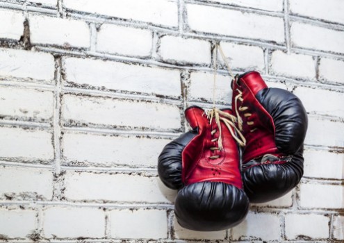 Bild på A pair of old boxing gloves hanging on white brick wall background