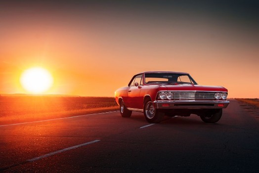 Bild på Retro red car standing on asphalt road at sunset