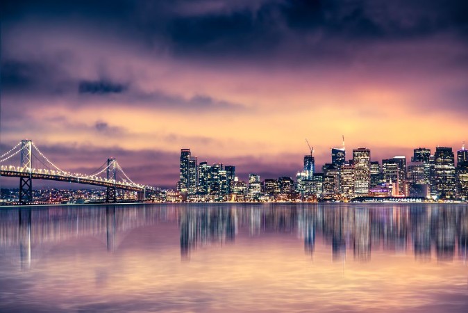 Picture of San Francisco California skyline with lights and bay under colorful sunset sky