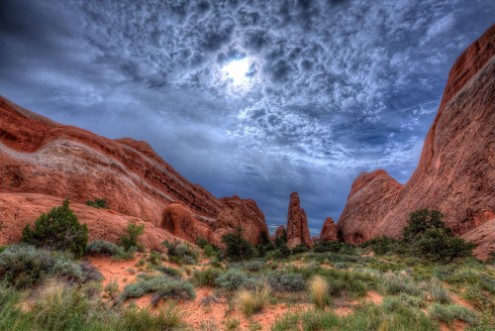 The sun trying to burn a hole through the encroaching storm clouds over the Utah landscape photowallpaper Scandiwall