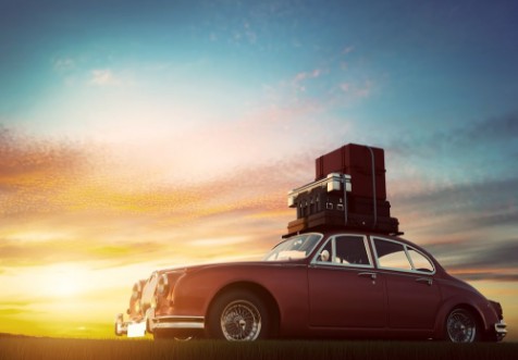 Afbeeldingen van Retro red car with luggage on roof rack at sunset Travel vacation concepts