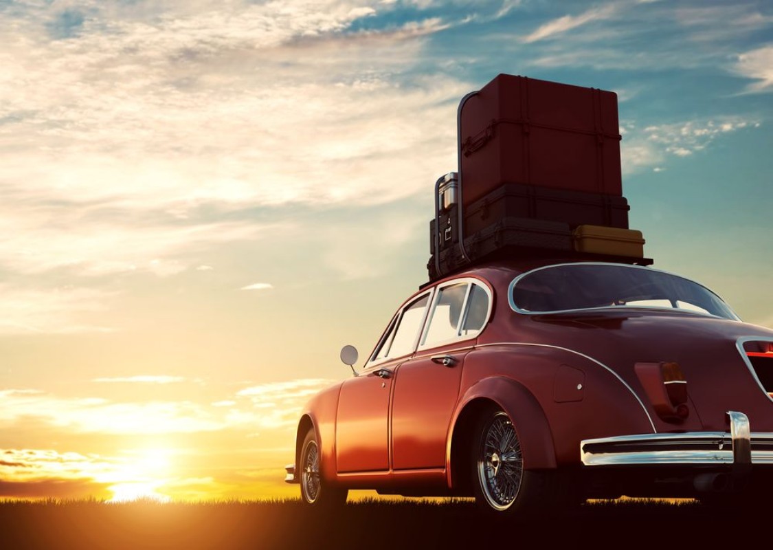 Afbeeldingen van Retro red car with luggage on roof rack at sunset Travel vacation concepts