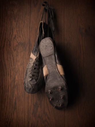 Afbeeldingen van Old used sports shoes on a rustic wooden wall