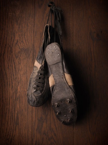 Afbeeldingen van Old used sports shoes on a rustic wooden wall