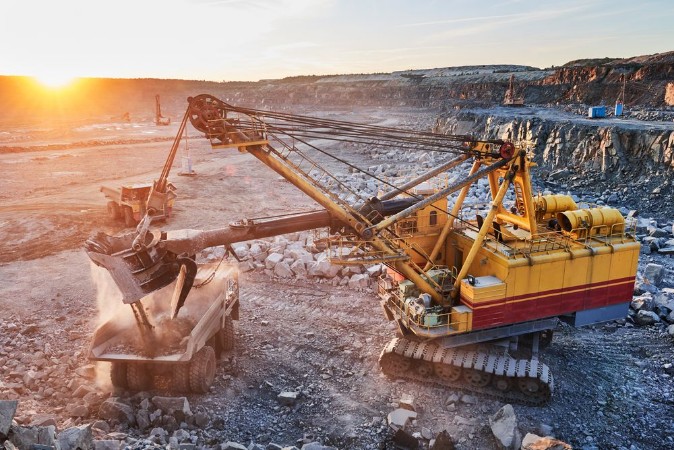 Afbeeldingen van Mining excavator loading granite or ore into dump truck