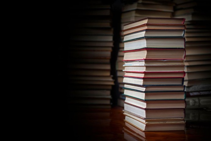 Picture of Stack of books against the background of a number of books a place for an inscription