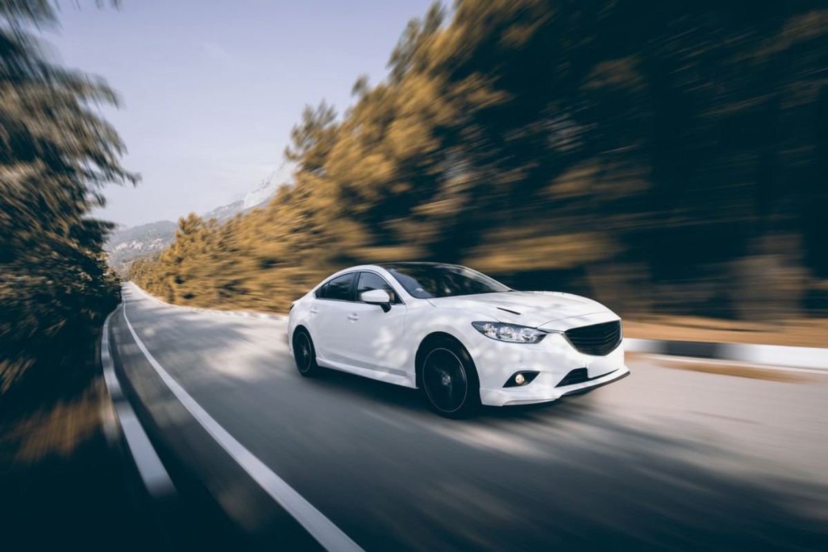 Afbeeldingen van White car speed driving on asphalt road at daytime