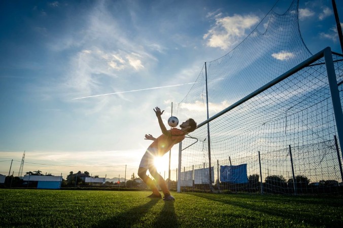 Afbeeldingen van Football player is training at the field on a sunset background