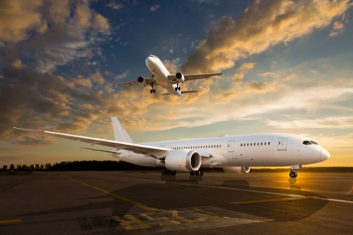 Bild på White passenger airplane on airport runway during sunset And aircraft in the sky
