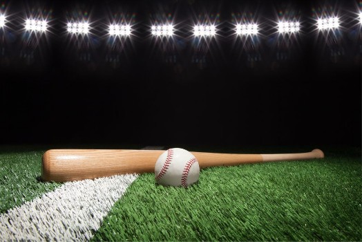 Picture of Baseball and bat at night under stadium lights on grass field