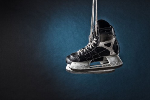 Picture of Mens hockey skates hanging on a dark background