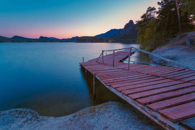 Afbeeldingen van Wooden pier on a blue lake sunset and smooth reflection on water Long exposure Borovoye Lake Kazakhstan