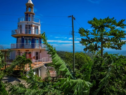 Bild på Roatan Honduras Lighthouse building Landscape of the island with a blue sky and green vegetation in the background
