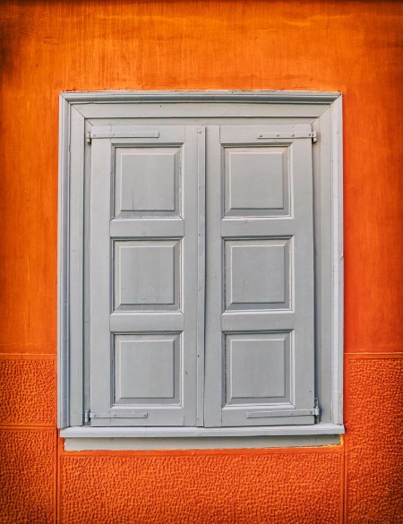 Picture of Grey closed shutters window on vibrant orange wall filtered