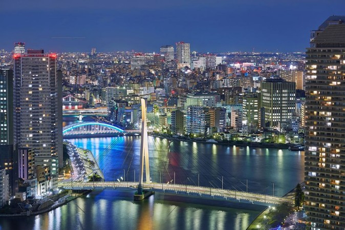 Picture of Night Tokyo panorama with wide angle aerial view of Sumida river in illuminated Tokyo with bright bridges skyscrapers and dark cloudy sky