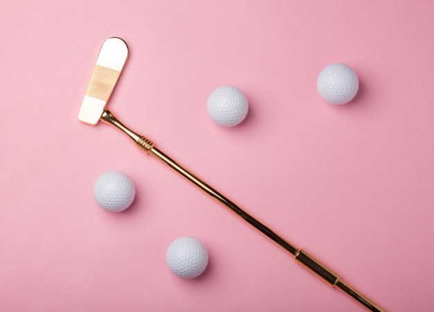 Bild på Luxury golden golf club with golf balls isolated on pink background