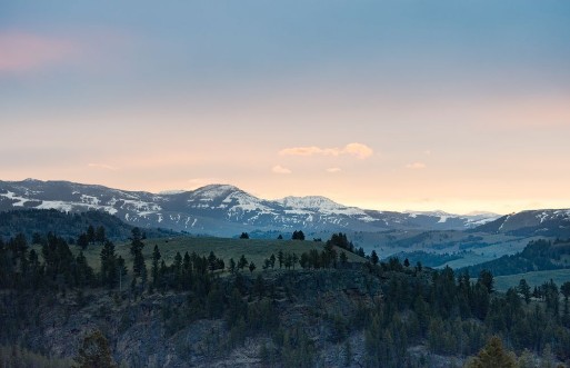 Picture of Panoramic view of sunrise over snow capped rugged mountains with smaller rocky hills in the foreground Photographed in natural light in Yellowstone National Park