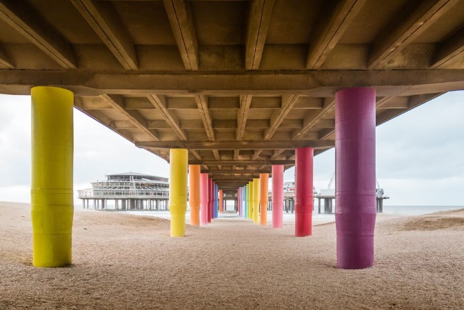 Bild på Shot under pier with color painted columns on the beach at sunset