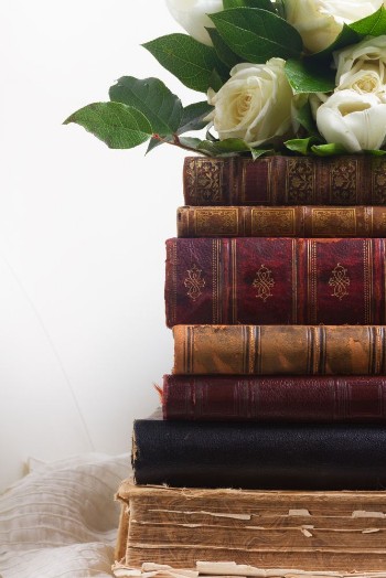 Bild på Old books with white flowers on romantic lace background close up