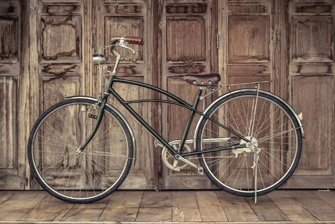 Picture of Vintage bicycle on vintage wooden house vintage tone Thai style vintage wooden door not Wood stain the door made of Teak wood Tectona grandis is Auspicious Tree in Thailand