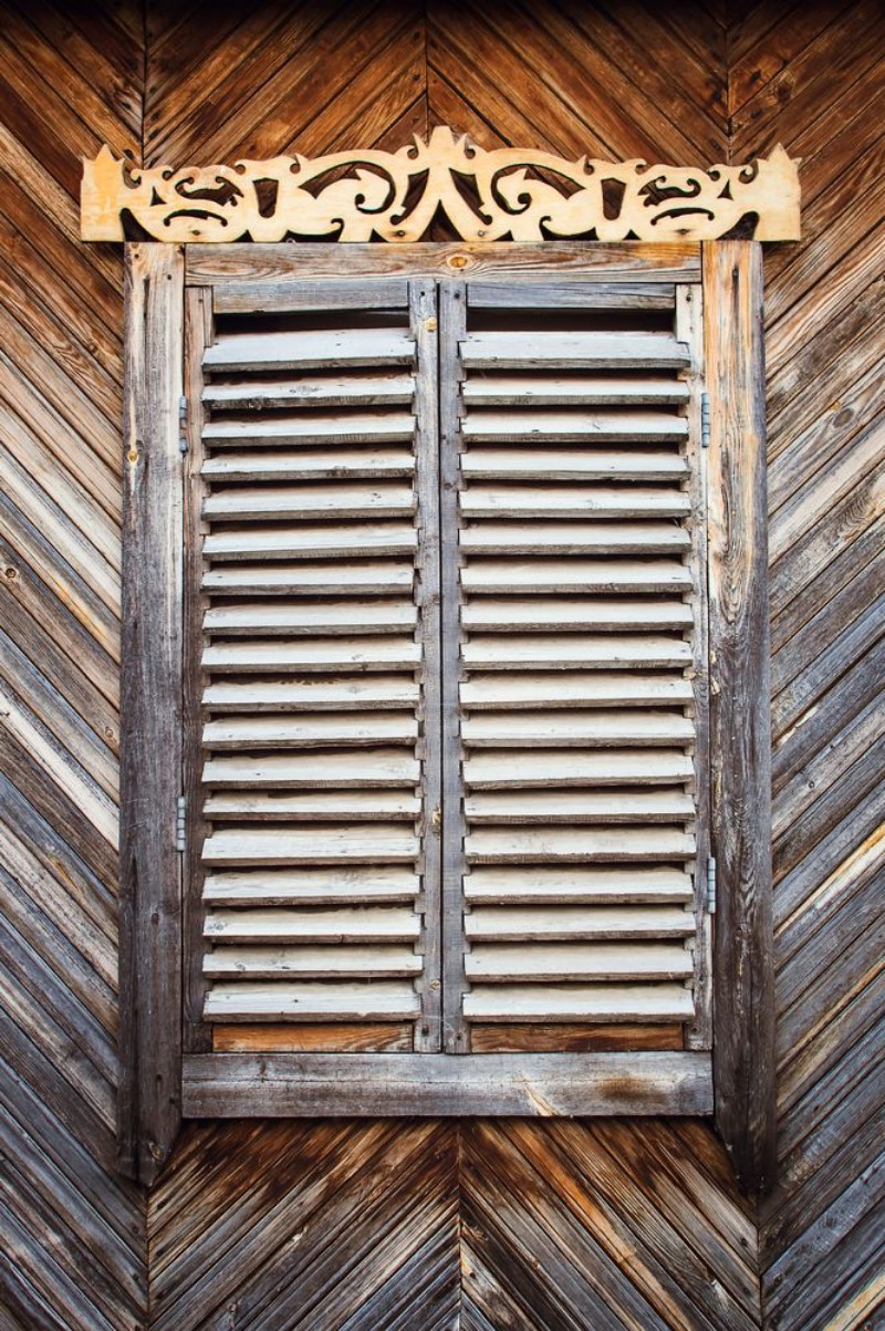 Afbeeldingen van The old weathered wooden closed window with hinges and carved shutters Retro