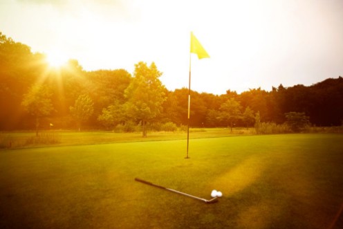 Image de Golfplatz im Abendrot mit Loch und Golfball und Fahne