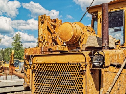 Picture of Old dirty yellow tractor or bulldozer is on the industrial site