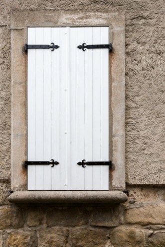 Image de White narrow wooden closed window shutters with metal ornaments