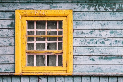 Afbeeldingen van Yellow window on green wooden wall of abandoned house