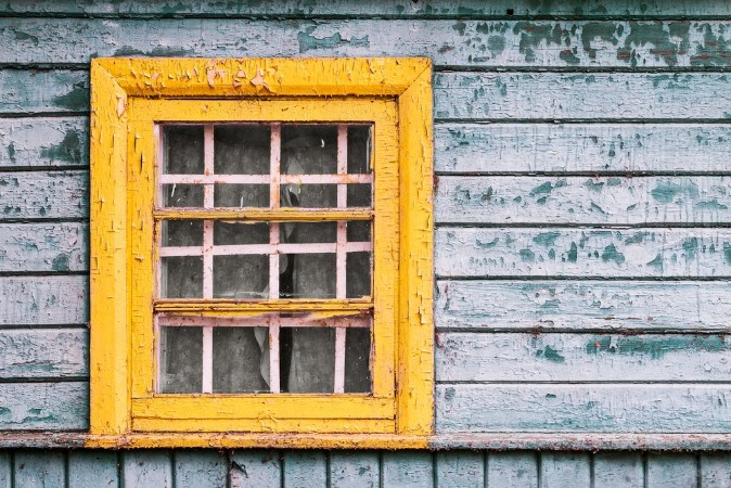 Picture of Yellow window on green wooden wall of abandoned house