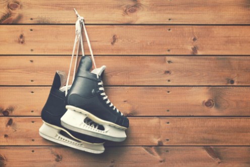 Afbeeldingen van Ice hockey skates hanging on nail on wooden plank background