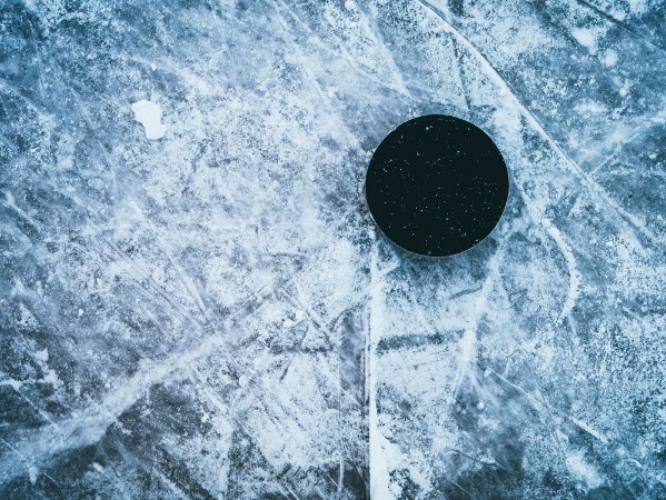 Afbeeldingen van Hockey puck on the ice and snow texture copyspace and text