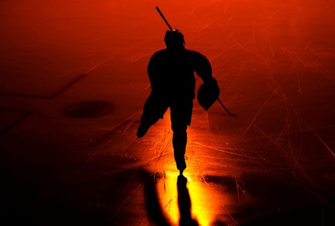 Afbeeldingen van One man ice hockey player in arena silhouette isolated on black background