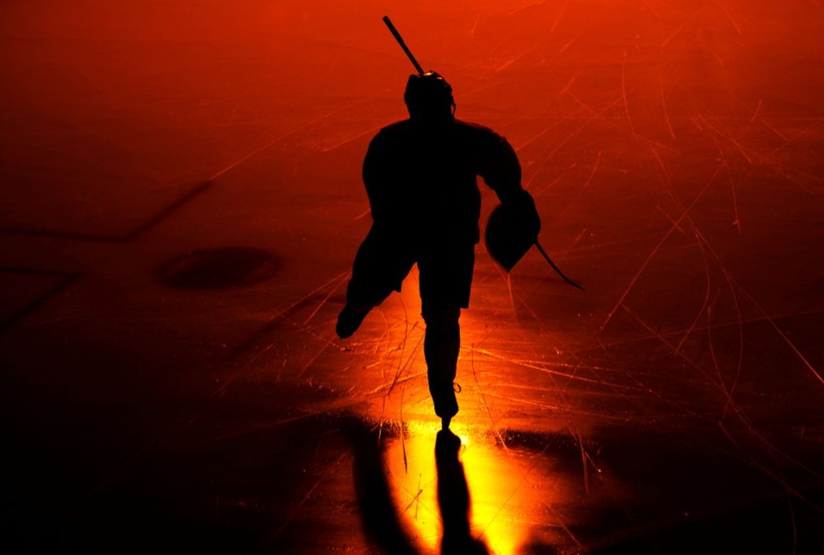 Afbeeldingen van One  man ice hockey player in arena silhouette isolated on black background