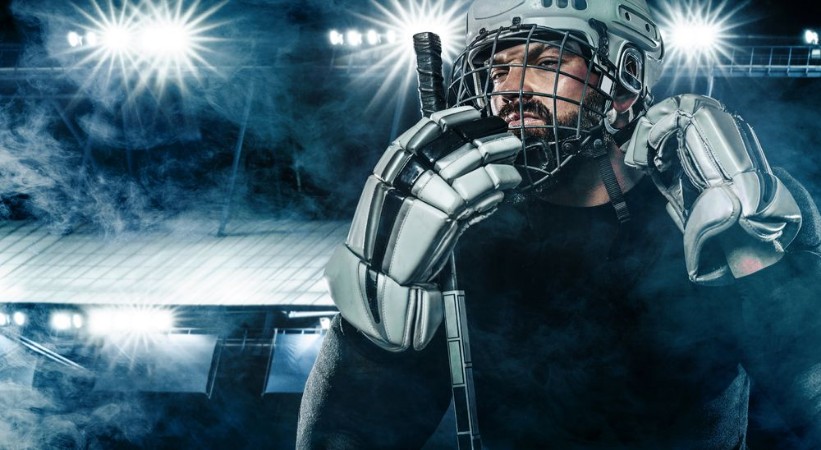 Afbeeldingen van Ice Hockey player in the helmet and gloves on stadium with stick