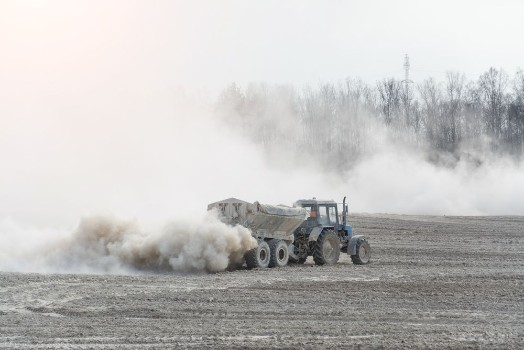 Picture of Tractor with trailer fertilizes agricultural field in spring for sowing corn