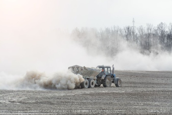 Image de Tractor with trailer fertilizes agricultural field in spring for sowing corn