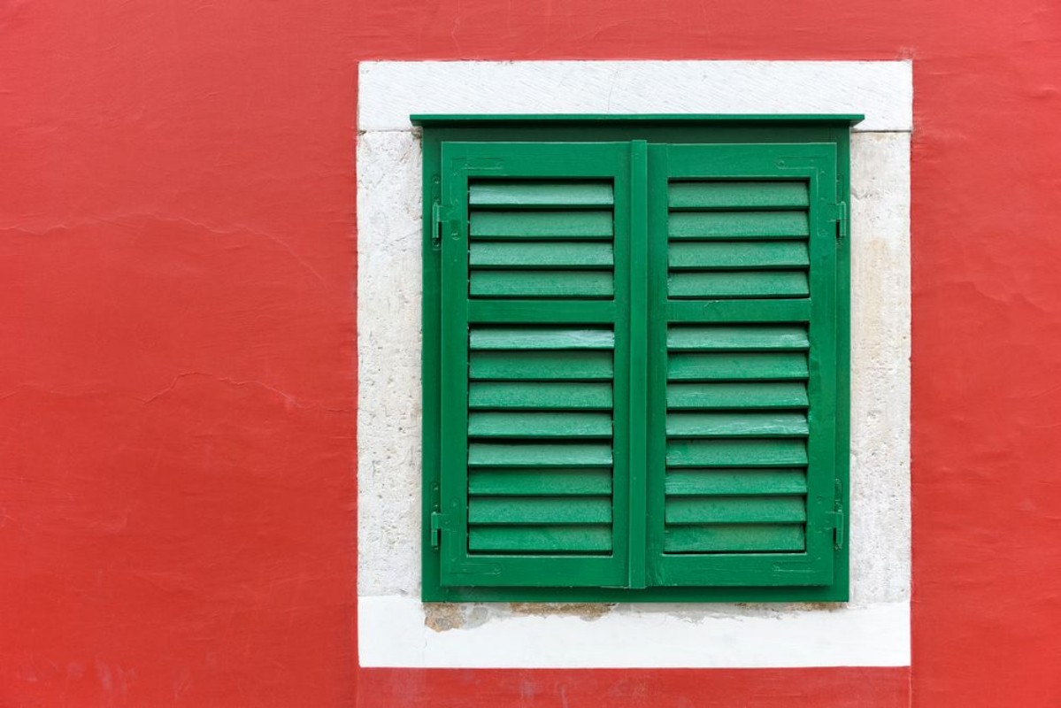 Afbeeldingen van Single window with green shutters set in red wall in Skradin