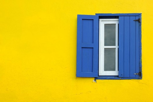 Bild på Colorful yellow house with blue shutters in Governors Harbour