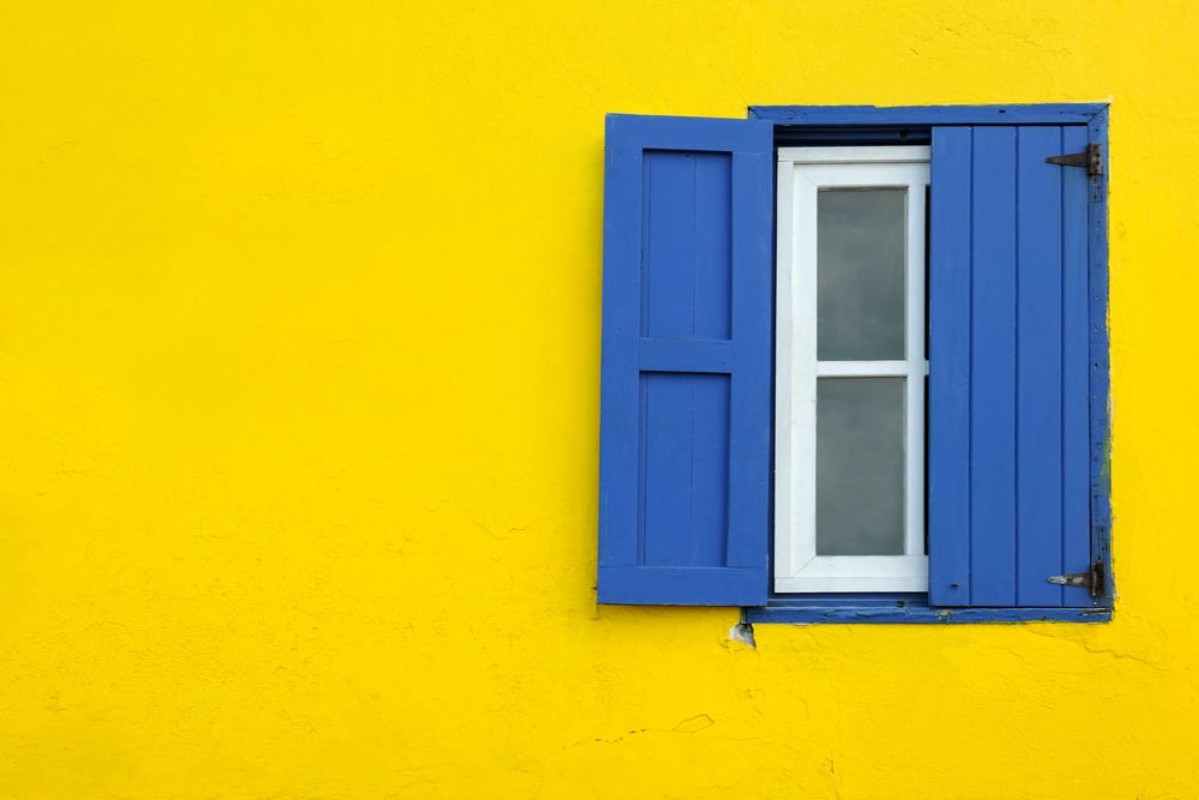 Afbeeldingen van Colorful yellow house with blue shutters in Governors Harbour