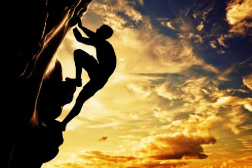 Bild på A silhouette of man climbing on mountain at sunset Adrenaline