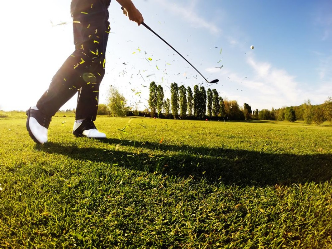 Afbeeldingen van Golfer performs a golf shot from the fairway