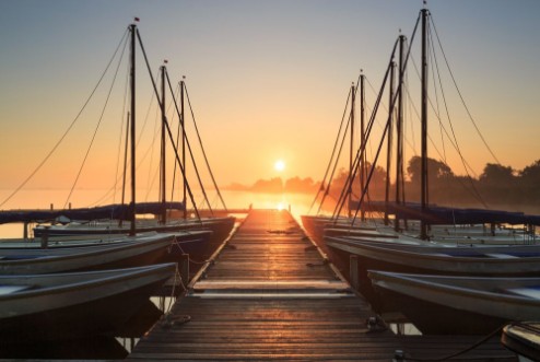 Picture of Tranquil foggy sunrise at a pier with sailing boats