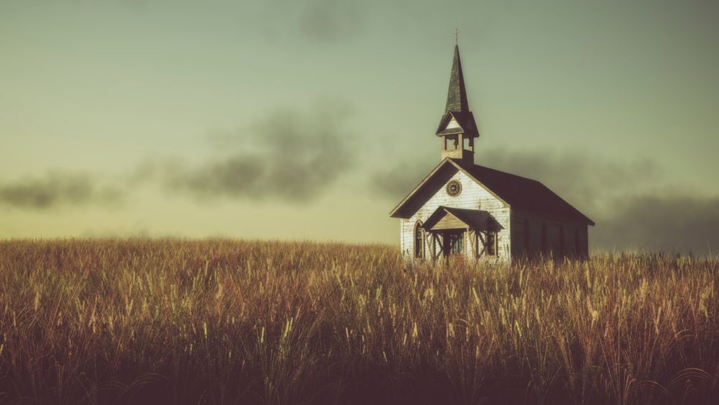 Picture of Old abandoned white wooden chapel on prairie at sunset with clou