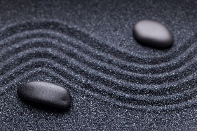 Afbeeldingen van Zen garden with a wave lines in the sand with irregular black st