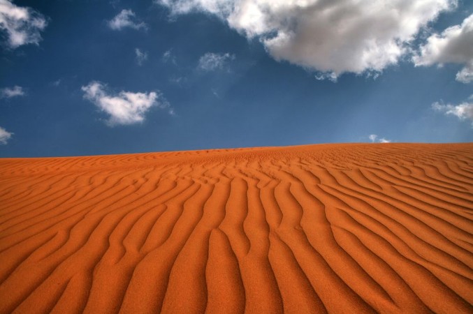 Afbeeldingen van Extensive Desert Under Blue Sky and White Clouds