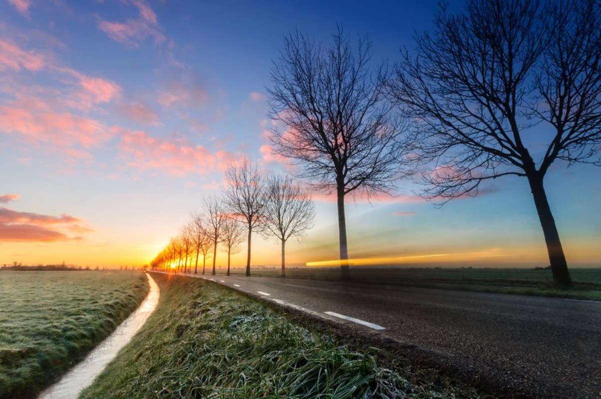 Afbeeldingen van A sunrise on a rural road cars passing by