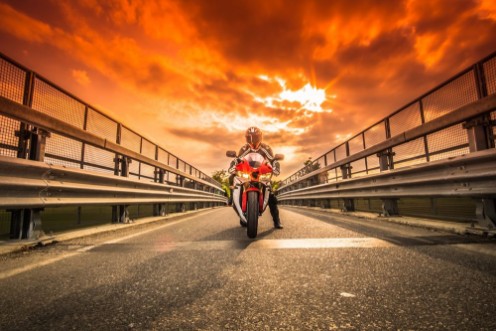 Afbeeldingen van Moto da strada pronta alla partenza sotto un cielo rosso al tramonto
