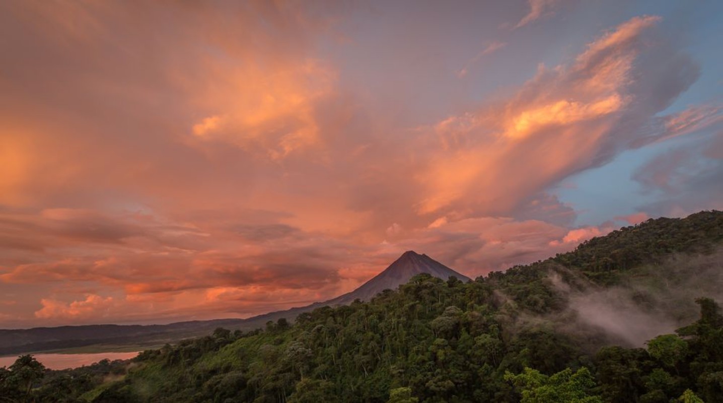 Picture of Sunset on Lake Arenal and Arenal Volcano in Costa Rica brings Shades of red and orange as clouds rise from the jungle floor