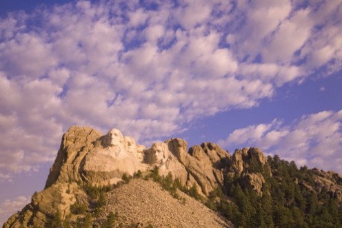 Afbeeldingen van White puffy clouds behind Presidents George Washington Thomas Jefferson Teddy Roosevelt and Abraham Lincoln at Mount Rushmore National Memorial South Dakota
